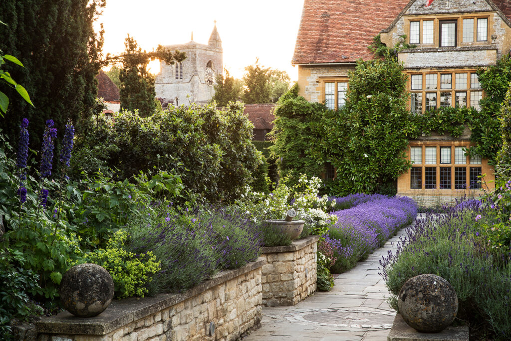 STOCK View of historic manor house from across a walled garden with path and lavender ©Getty