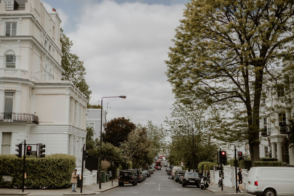 London tree-lined street with white mansion houses and red buses